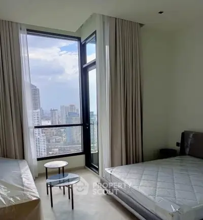 Modern bedroom with city view and floor-to-ceiling windows in high-rise apartment.