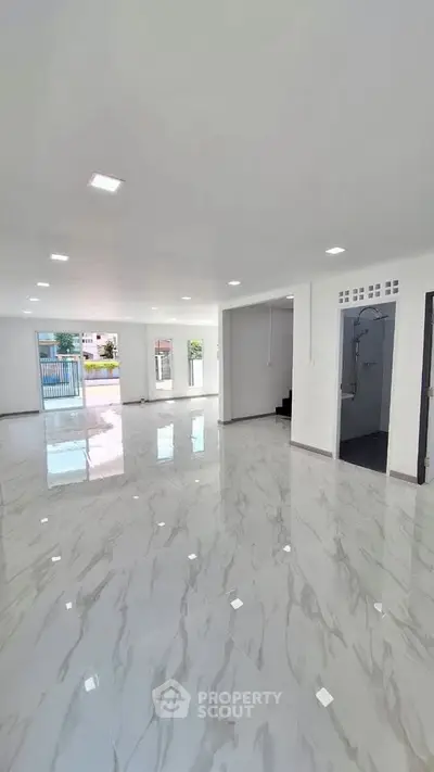 Spacious modern living room with glossy marble floors and ample natural light.