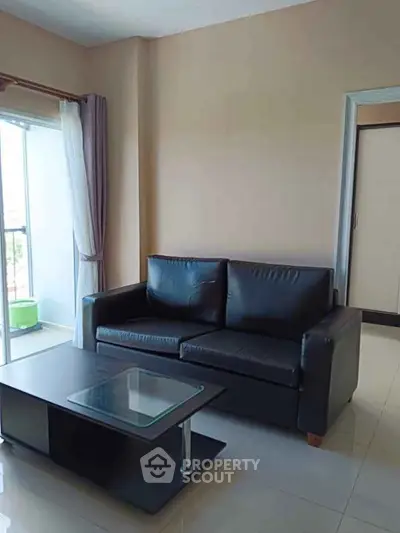 Modern living room with sleek black sofa and glass coffee table, bright natural light.