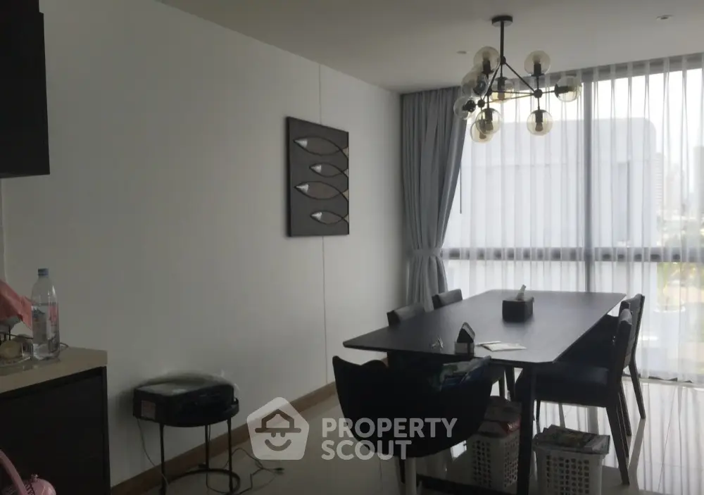 Modern dining area with stylish chandelier and large window view.