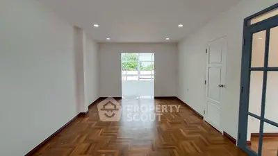 Spacious empty room with wooden flooring and large window