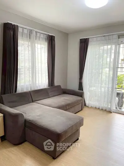 Spacious living room with large sofa and natural light from big windows.