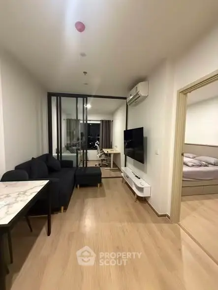 Modern living room with sleek furniture and open layout, featuring a cozy bedroom view.