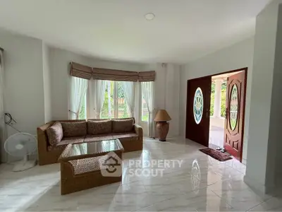 Spacious living room with elegant decor and large windows offering garden views.