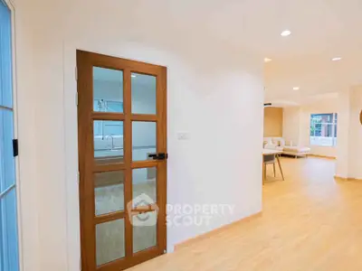 Spacious open-plan living area with wooden flooring and glass door, perfect for modern living.