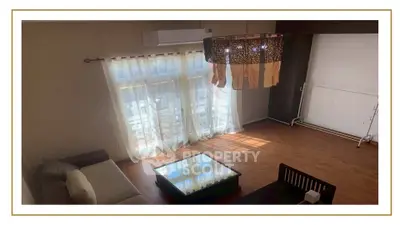 Spacious living room with elegant chandelier and large windows offering natural light.