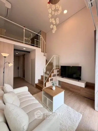 Modern living room with high ceiling and mezzanine, featuring elegant decor and cozy seating area.