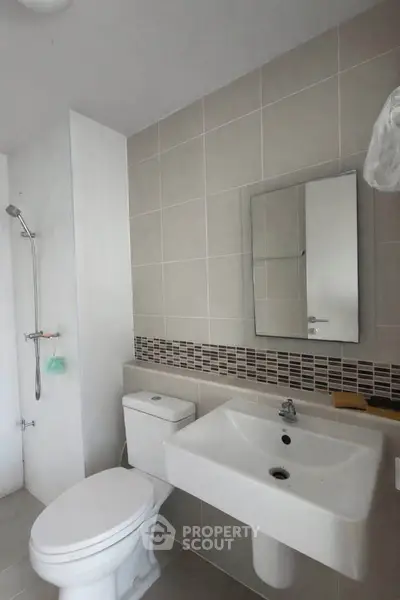Modern bathroom with sleek fixtures and neutral tiles, featuring a shower and a large mirror.