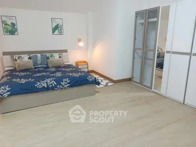 Spacious bedroom with modern decor and large mirrored wardrobe