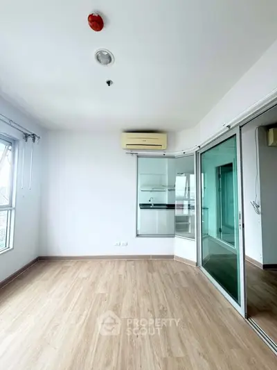 Spacious unfurnished room with wooden flooring and large windows in modern apartment.