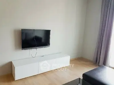 Minimalist living room with wall-mounted TV and sleek white cabinet.