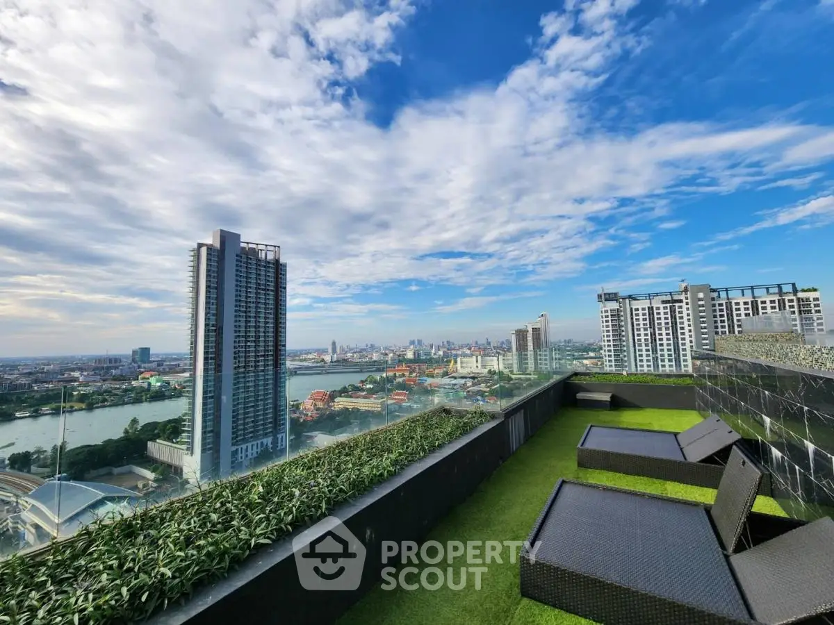 Stunning rooftop view with city skyline and river, featuring modern lounge chairs and lush greenery.