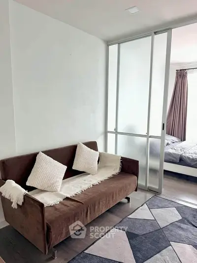 Modern apartment with cozy living area and sliding glass doors leading to bedroom.