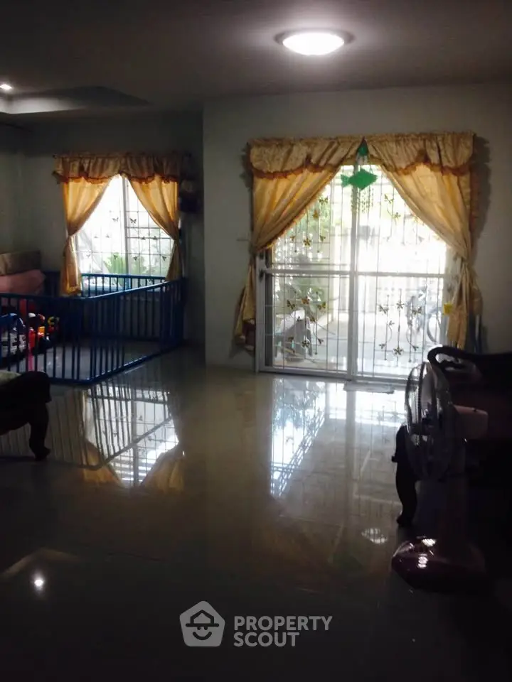 Spacious living room with large windows and elegant curtains, perfect for family gatherings.