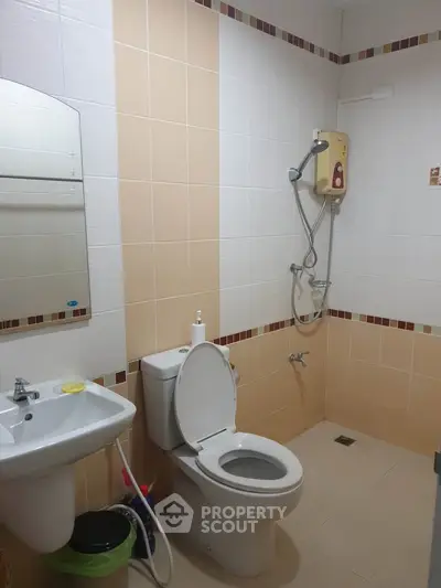 Modern bathroom with shower, toilet, and sink in a clean, tiled setting.