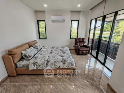 Spacious bedroom with large windows and modern furnishings, offering a serene view and ample natural light.