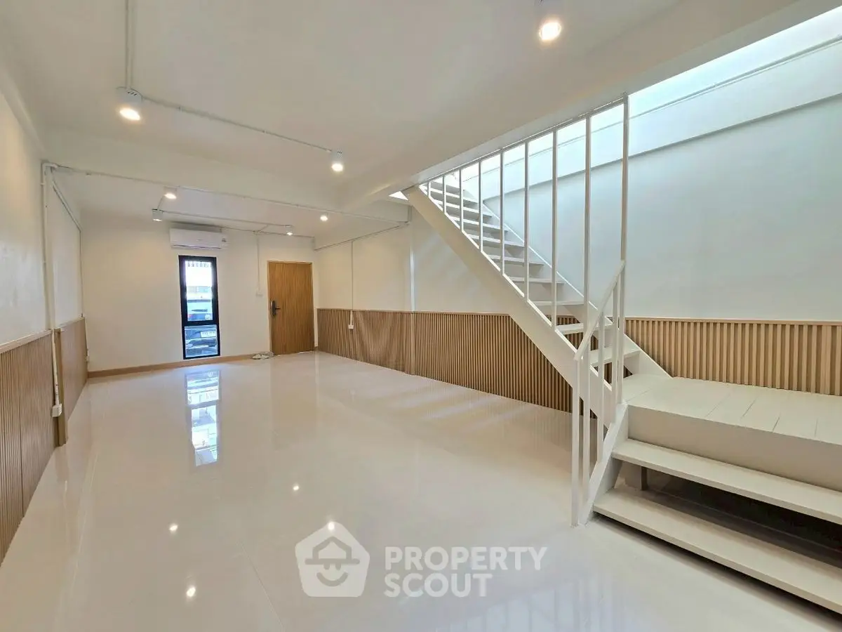 Spacious modern living room with sleek staircase and bright lighting