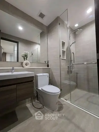 Modern bathroom with glass shower, sleek vanity, and elegant fixtures in contemporary apartment.