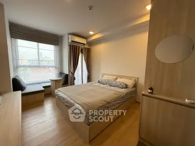 Modern bedroom with large window, cozy seating area, and stylish wooden furniture.