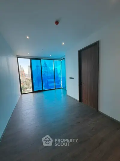 Spacious modern room with floor-to-ceiling windows offering stunning city views, perfect for urban living.