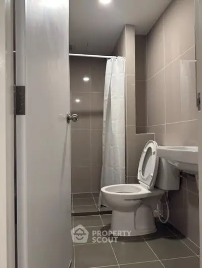 Modern bathroom with sleek tiles and shower curtain in contemporary apartment.