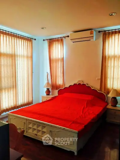 Cozy bedroom with red bedding and natural light from large windows