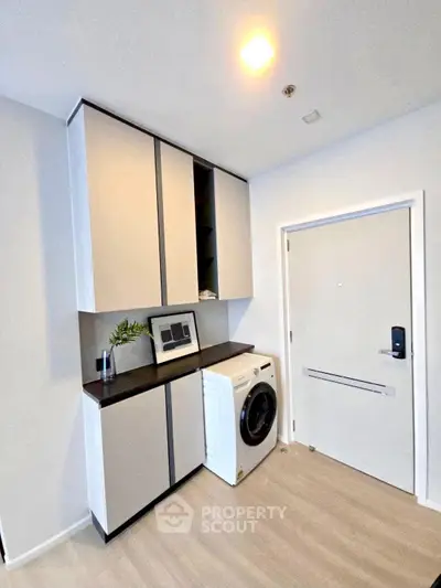 Modern laundry area with sleek cabinets and washing machine in stylish apartment.