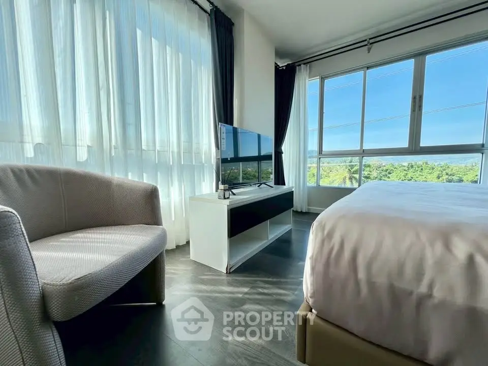 Bright bedroom with large windows and scenic view, featuring modern furniture and sleek flooring.