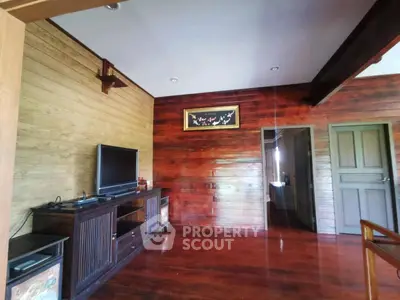 Charming rustic living room with wooden walls and flooring, featuring a TV and elegant decor.