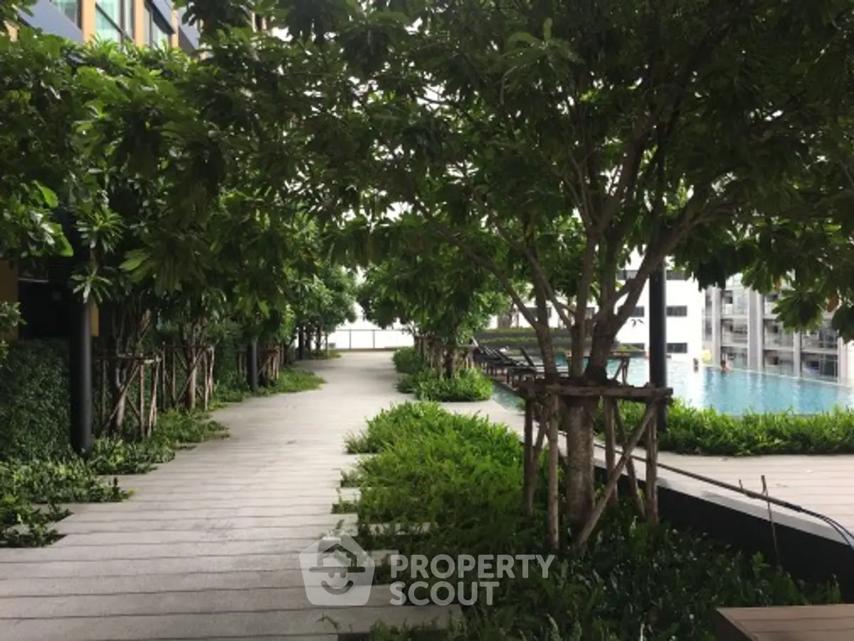 Luxurious garden pathway leading to a serene poolside oasis in a modern residential complex.