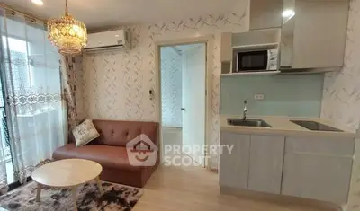 Chic modern living room with cozy sofa, elegant chandelier, and compact kitchen in open layout apartment.