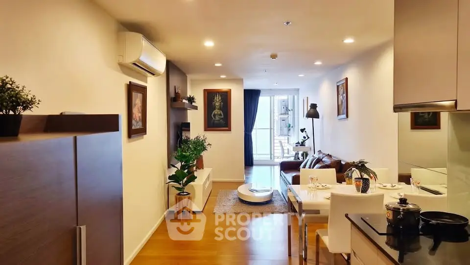 Modern living room with open kitchen, stylish decor, and cozy seating area leading to a balcony.
