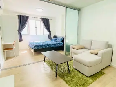 Modern studio apartment with cozy living area and bedroom, featuring stylish furniture and natural light.