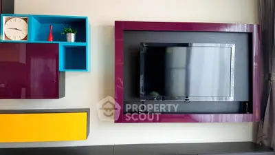 Modern living room with stylish TV setup and colorful shelving