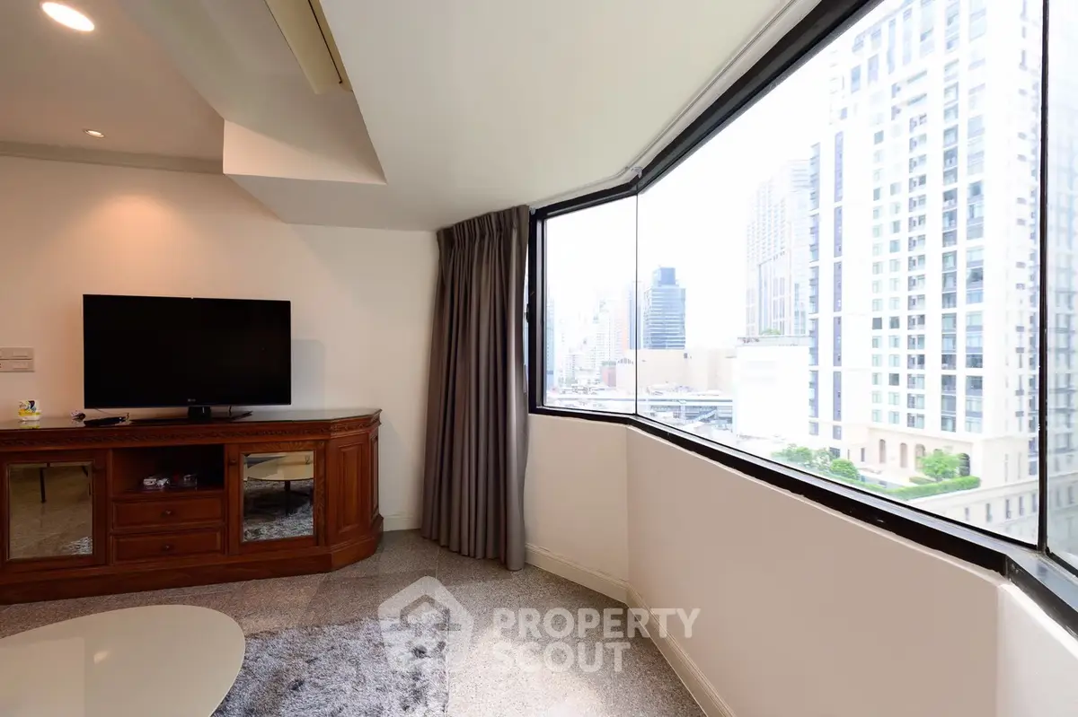 Spacious living room with large window offering stunning city views in a modern apartment.
