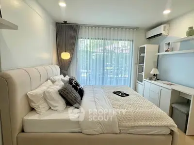 Cozy bedroom with modern decor and large window offering natural light
