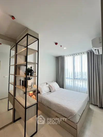 Modern bedroom with stylish shelving and large window offering natural light.