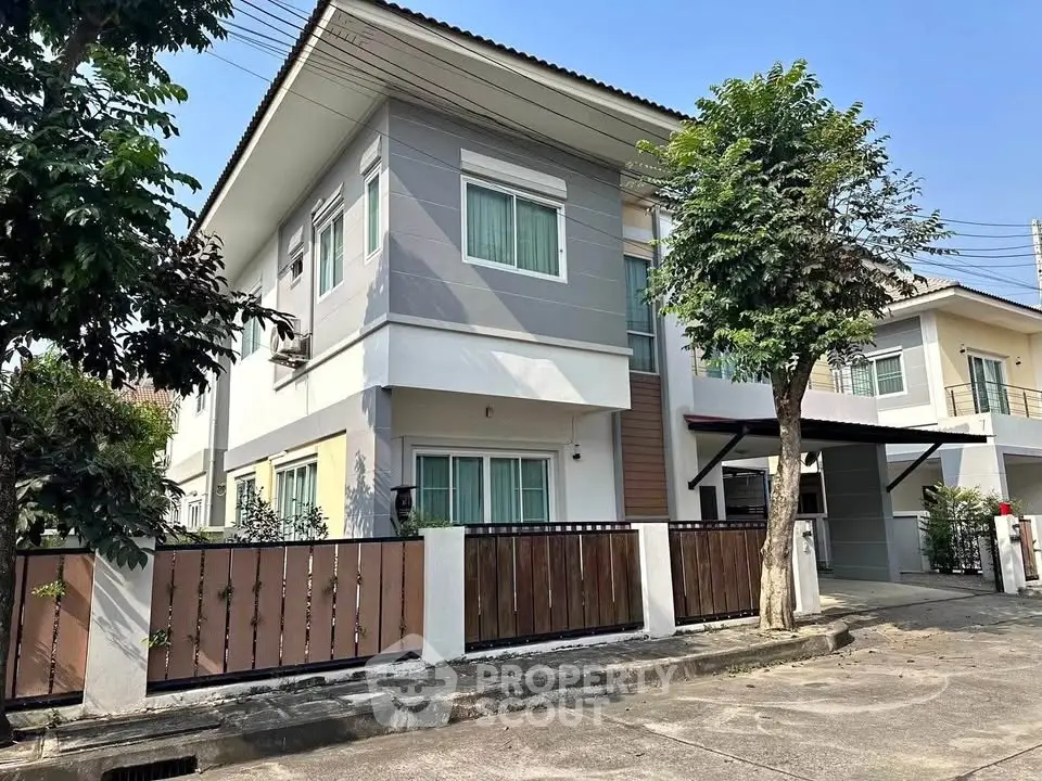 Modern two-story house with a fenced yard and driveway in a suburban neighborhood.