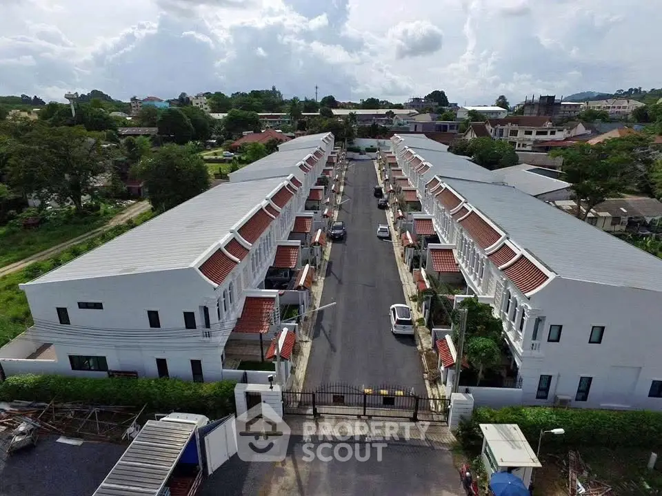 Aerial view of modern townhouse complex with gated entrance and lush surroundings.