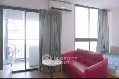 Modern apartment interior with red sofa, large windows, and balcony access.