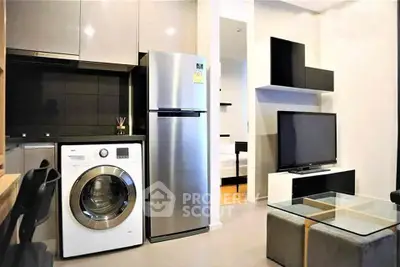Modern apartment interior with sleek kitchen and cozy living area featuring a washing machine and stainless steel fridge.