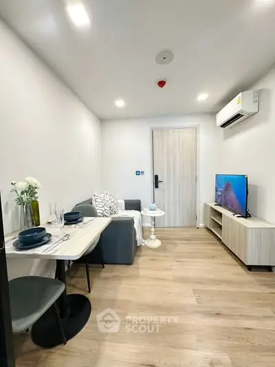 Modern living room with stylish decor, cozy seating, and sleek TV setup in a compact apartment.