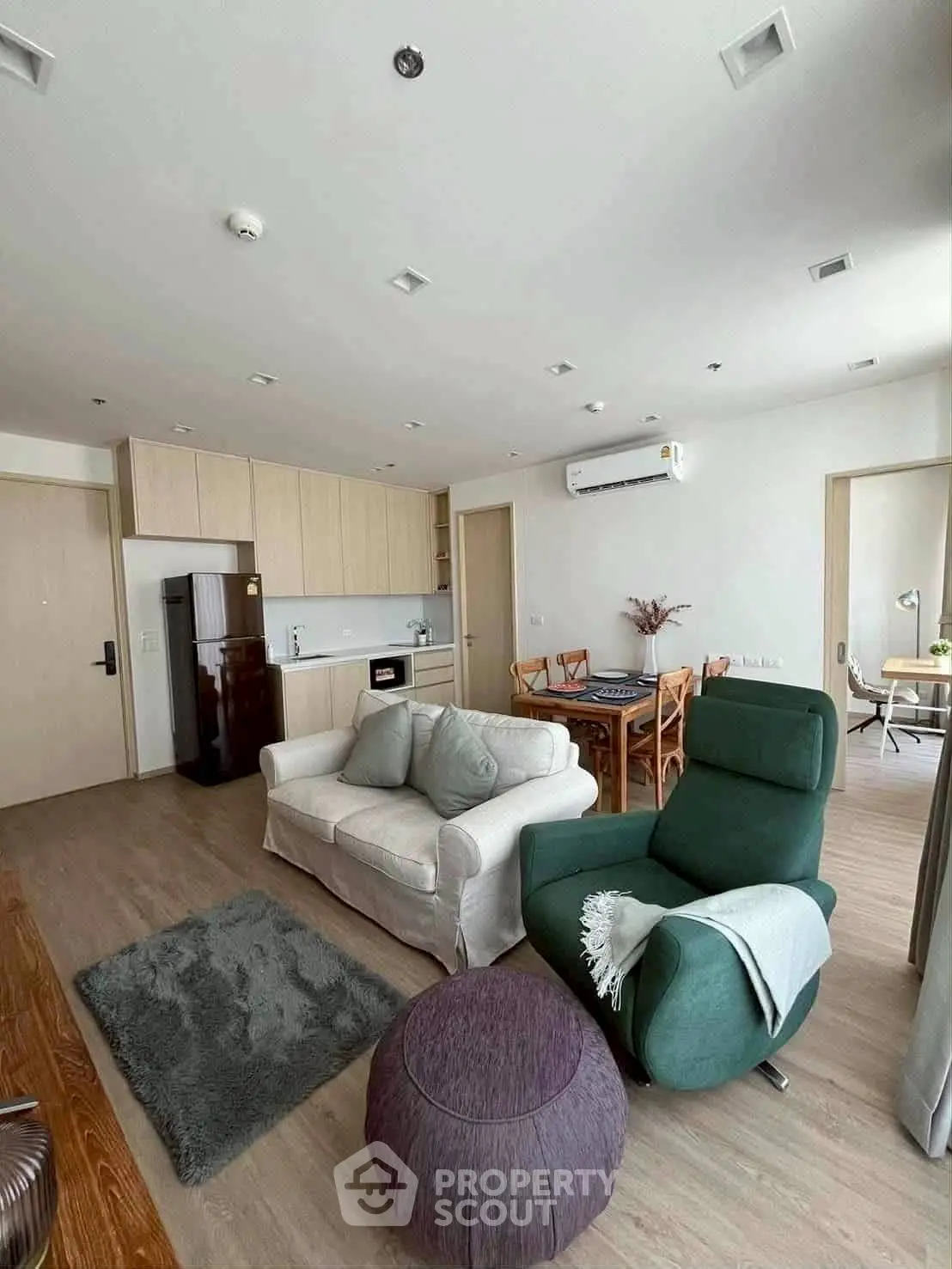 Modern living room with open kitchen, featuring cozy seating and stylish decor in a contemporary apartment.