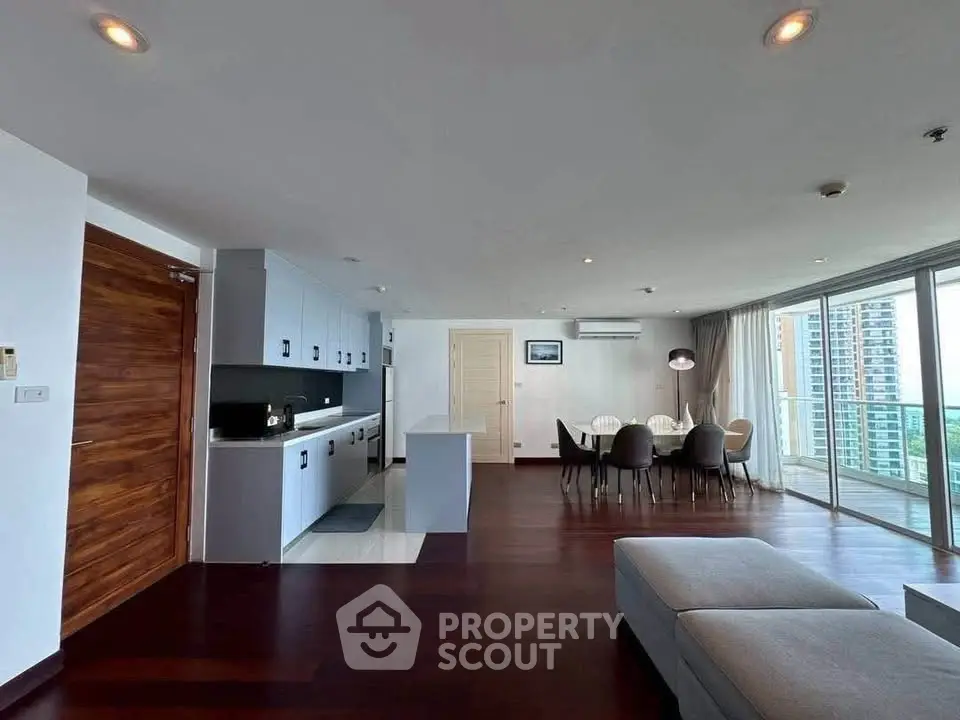 Spacious modern living room with open kitchen and city view, featuring elegant dining area and sleek design.
