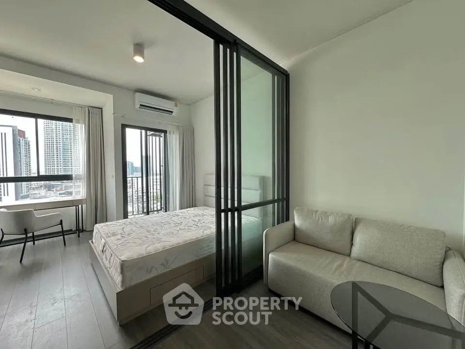 Modern condo bedroom with glass partition and city view, featuring a cozy sofa and sleek design.