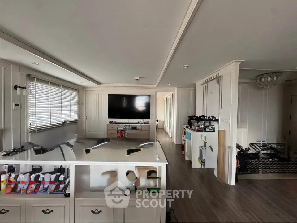Spacious living room with modern decor and large TV, featuring elegant wood flooring and ample natural light.