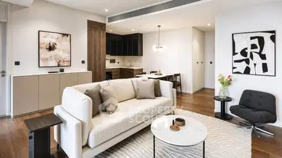 Modern living room with stylish decor and open kitchen layout, featuring elegant furniture and contemporary art.