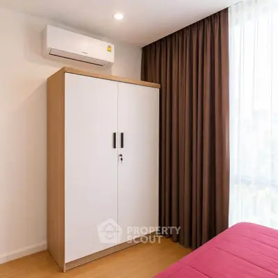 Modern bedroom with air conditioning and wardrobe, featuring elegant curtains and wooden flooring.