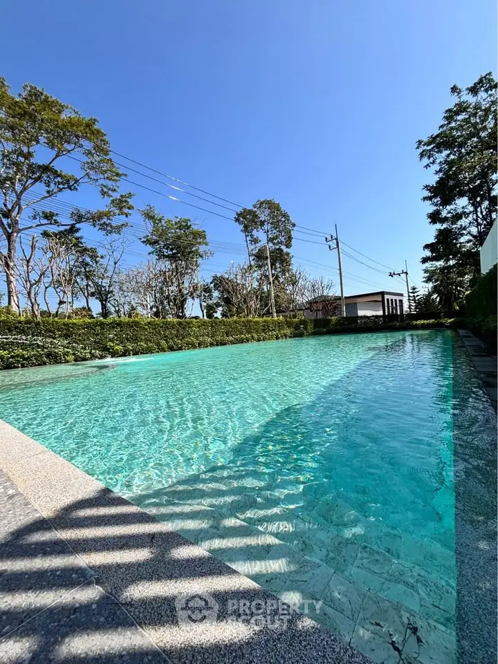 Luxurious outdoor pool with crystal-clear water and lush greenery, perfect for relaxation and leisure.