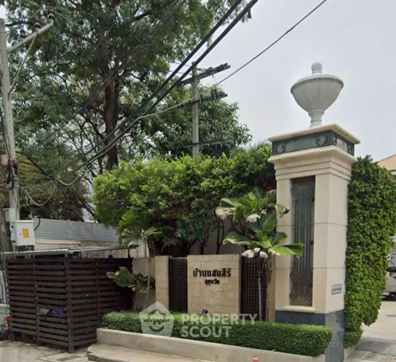 Elegant entrance of a residential property with lush greenery and classic architectural details.
